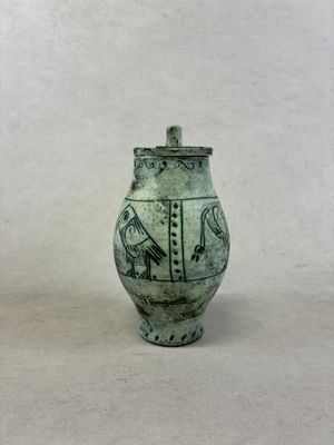 un petit vase avec un oiseau posé sur une table