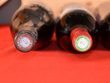 three bottles of wine are lined up on a red cloth
