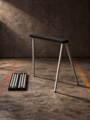 un tabouret noir posé par terre à côté de deux bâtons