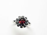 un gros plan d'une bague ornée d'une pierre rouge entourée de diamants noirs