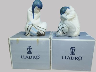 pair of ceramic figurines of a man and a woman sitting on a box