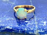 un gros plan d'une bague en or sertie d'une pierre oplite blanche