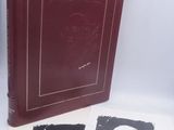 Le livre est posé sur une table, à côté de deux photos en noir et blanc.