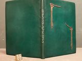 an old green book sitting on top of a table next to a pair of scissors