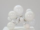 une image d'une sculpture composée de boules de verre posées sur un socle blanc