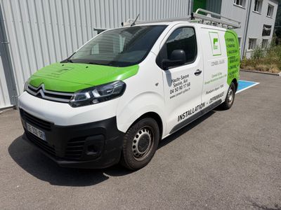 une camionnette blanche aux finitions vertes garée devant un immeuble