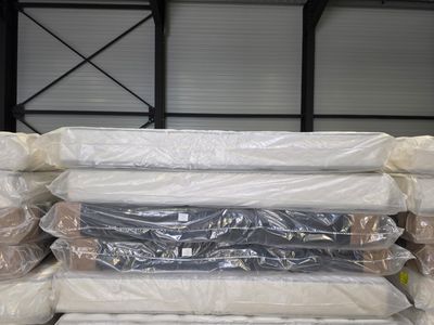 a lot of mattresses stacked on top of each other in a warehouse