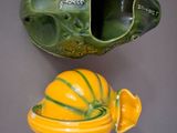 a green and yellow vase and a yellow pumpkin on a gray surface