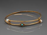 un gros plan sur un bracelet en or orné de perles et d'une pierre turquoise