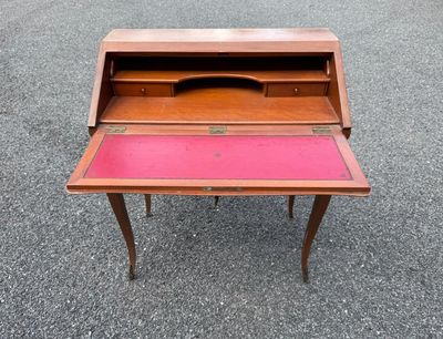 un vieux bureau en bois au plateau rose posé sur du gravier