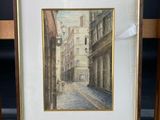 painting of a street scene in a frame on a wooden easel