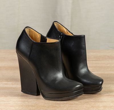 a pair of black leather ankle boots on a wooden table