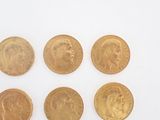 six gold sovereigns of different sizes and shapes on a white surface