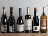 several bottles of wine are lined up on a wooden table