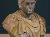 a bust of a man sitting on a table next to a vase