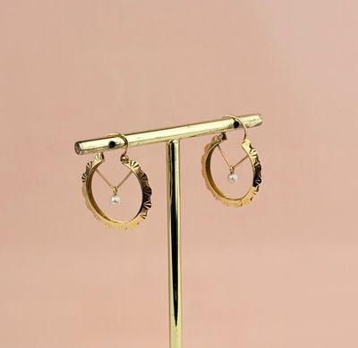 une paire de boucles d'oreilles créoles en or posées sur un présentoir en or