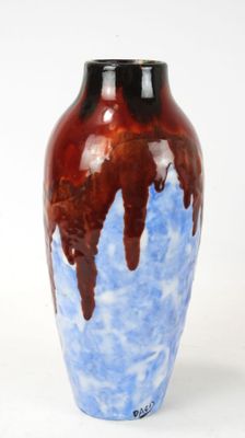 a blue and brown vase sitting on a white surface