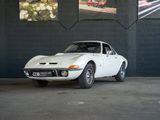 une voiture blanche garée dans un garage, avec des photos accrochées au mur derrière elle