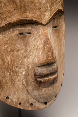 une photo en gros plan d'un masque en bois posé sur un socle