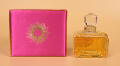 a close up of a bottle of perfume next to a pink box