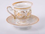 une tasse et une soucoupe sur une soucoupe sur une surface blanche