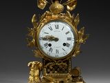 a gold clock with a bird on top of it