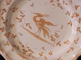 two plates with gold designs on them on a black surface