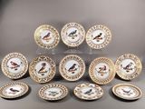 douze assiettes en porcelaine ornées d'oiseaux peints sont disposées en pyramide