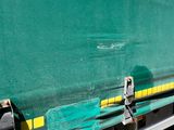 a green and yellow train on the tracks next to a building