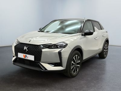 Une voiture blanche est garée dans une pièce au sol noir.