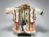 a white and brown fur coat with a bell hanging from it ' s neck
