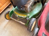 two lawn mowers parked next to each other in a garage