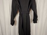 the back of a black coat is hanging on a white curtain
