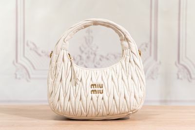 white handbag on a wooden table with a wall in the background