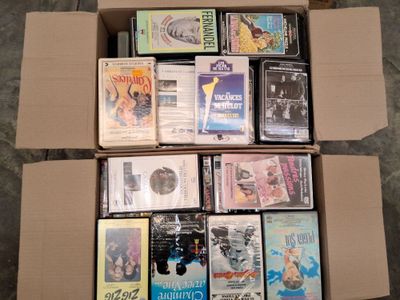 un grand nombre de DVD dans une boîte en carton posée sur le sol