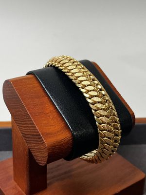 bracelet posé sur un présentoir en bois, sur lequel est posé un bracelet noir et doré