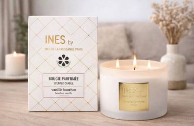 une bougie blanche posée sur une table en bois, à côté d'une boîte