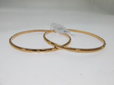 deux bracelets rigides de couleur dorée, sur lesquels sont gravés des mots