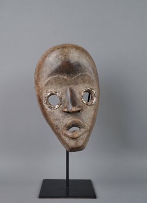 un gros plan d'un masque posé sur un support, sur fond gris