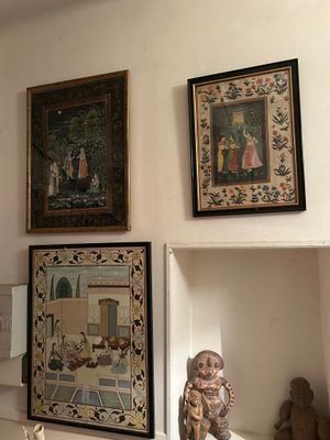 de nombreux tableaux accrochés au mur au-dessus d'une étagère dans une pièce