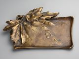 brass plate with leaves and flowers on it on a gray surface