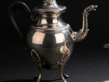une théière en argent et une assiette en argent posées sur une table