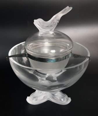 a glass bowl with a bird on it and a spoon in the bowl