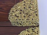 a small wooden box with a gold decoration on it
