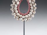 un collier composé de coquillages et de perles rouges, monté sur un support