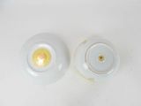 pair of white porcelain bowls with gold rims on a white surface