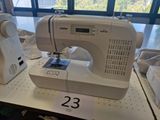 a white sewing machine sitting on a table in front of a window