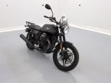 a black motorcycle parked in a room with a white wall