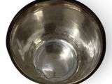 a metal bowl that is sitting on a white surface