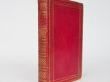 un vieux livre rouge posé sur une surface blanche